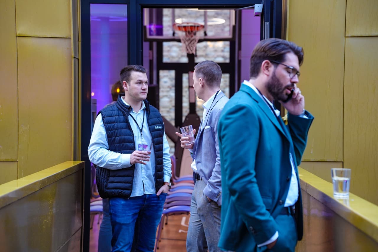 Teilnehmer beim MUUUH! Walk-Event im Networking-Bereich: Männer im Gespräch, einer telefoniert, festliche Atmosphäre