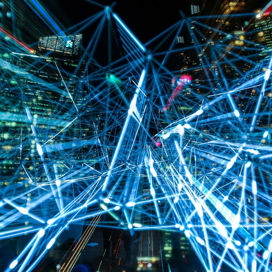 Leuchtendes Datennetzwerk aus blauen Linien über nächtlicher Stadtlandschaft